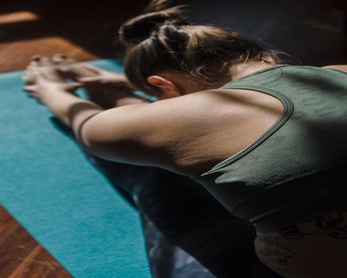 A person stretching and relaxing on a yoga mat in a sunny room