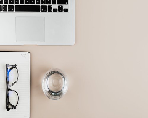 A calm working space with a laptop, notebook, and a glass of water